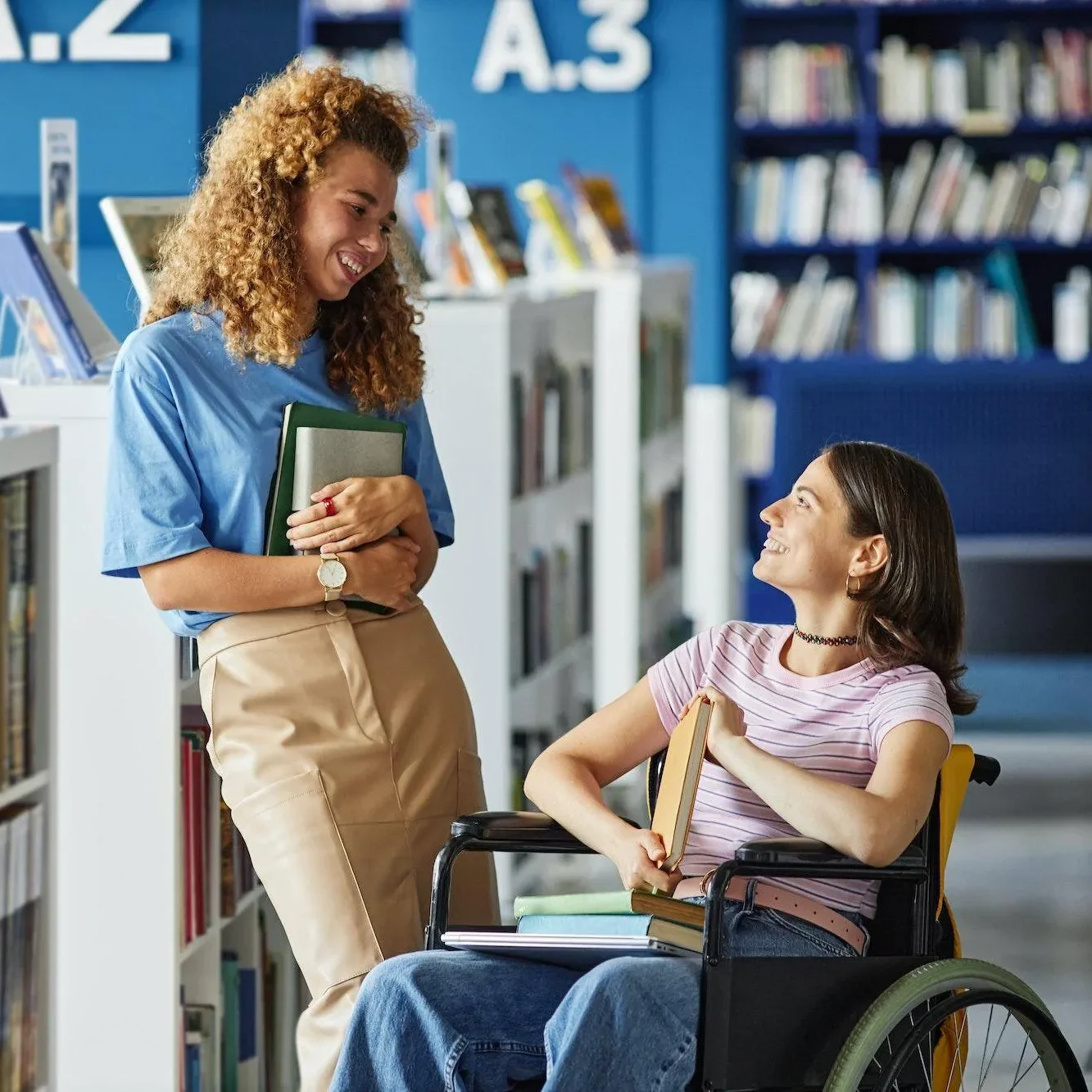 disabled women on wheelchair in library chatting with a friend