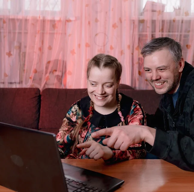 disabled young girl watching a movie and smiling with caretaker