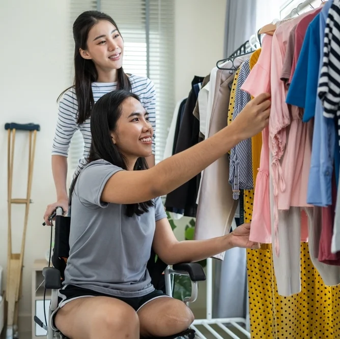 Women helping disabled sister pick clothes in wheelchair
